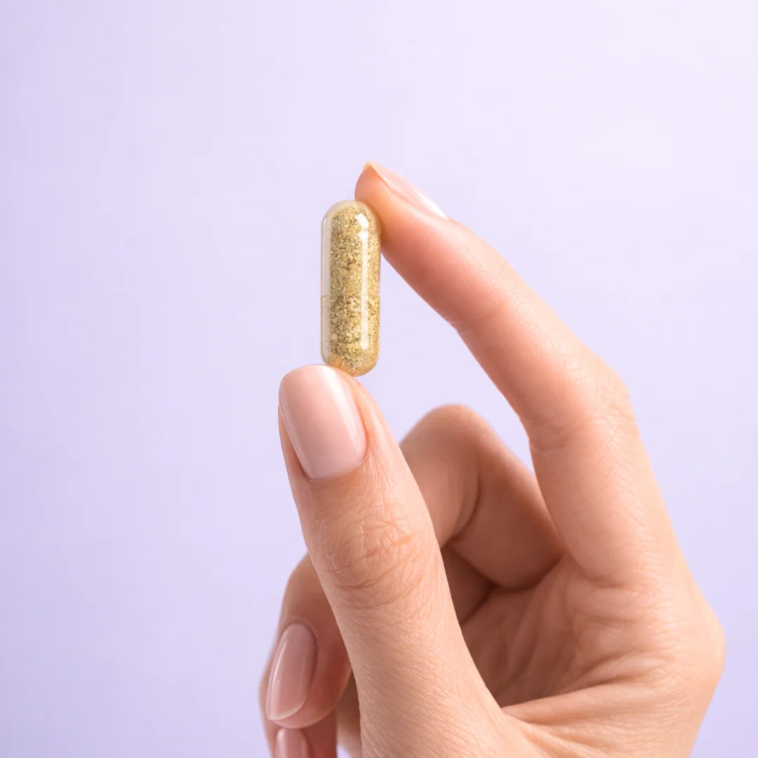 Hand holding a gold-colored supplement capsule of Balance by ARYA Lab against a light purple background