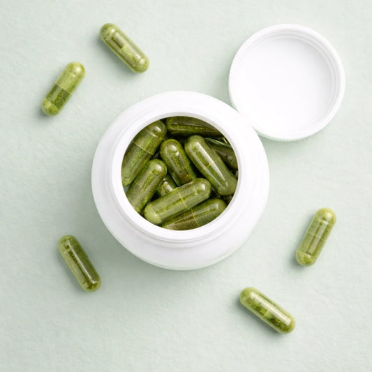 Green supplement capsules of Glow by ARYA LAB in a white container on a light green background
